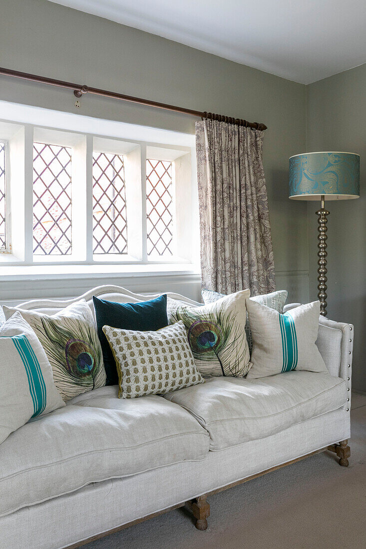 Weißes Sofa mit blaugrünen Kissen im Bleiglasfenster eines unter Denkmalschutz stehenden jakobinischen Hauses in Alton UK