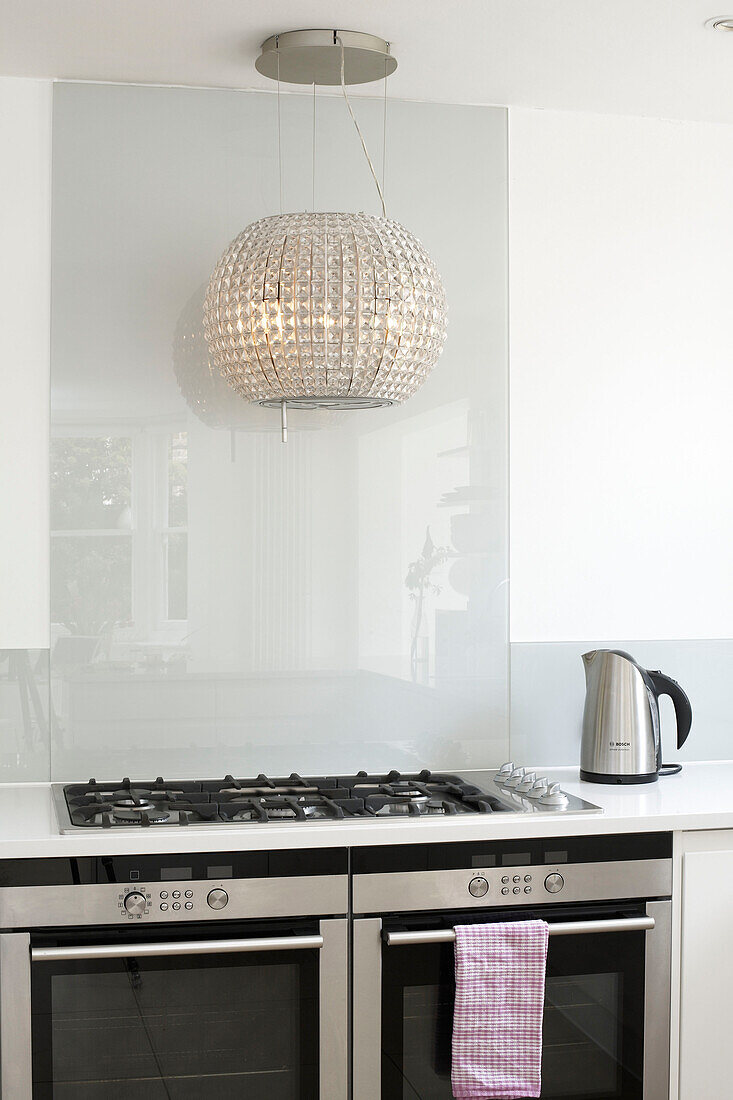 Metallic lampshade above hob unit with kettle in London home