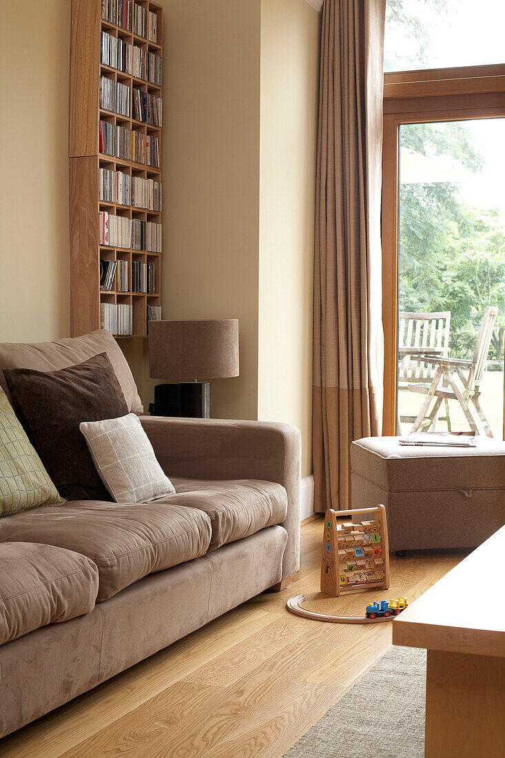 Child's abacus and train track on floor of London home with wooden bookcase and light brown sofa