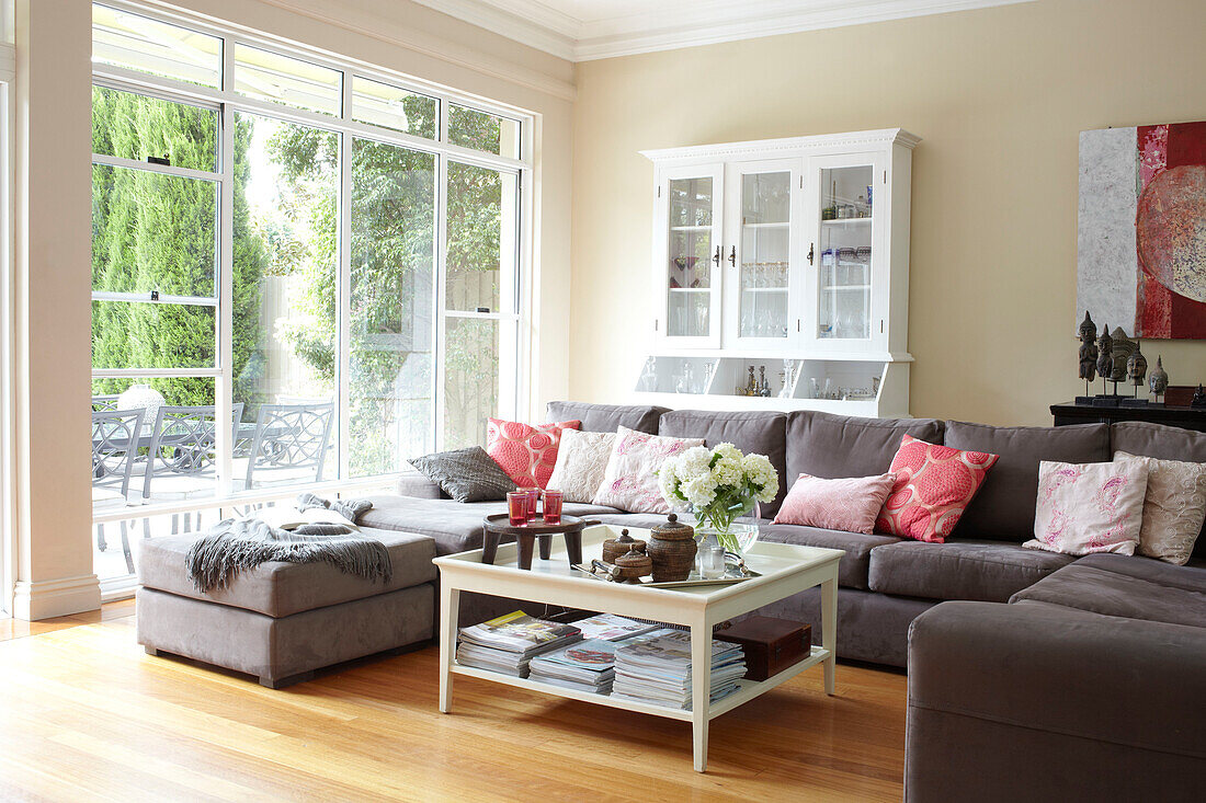 Grey corner sofa with white painted coffee table and cabinet in Sydney home Australia