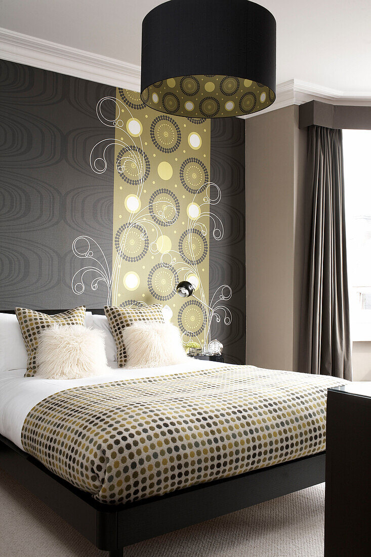 Double bed with spotted duvet and co-ordinating wallpaper and lampshade