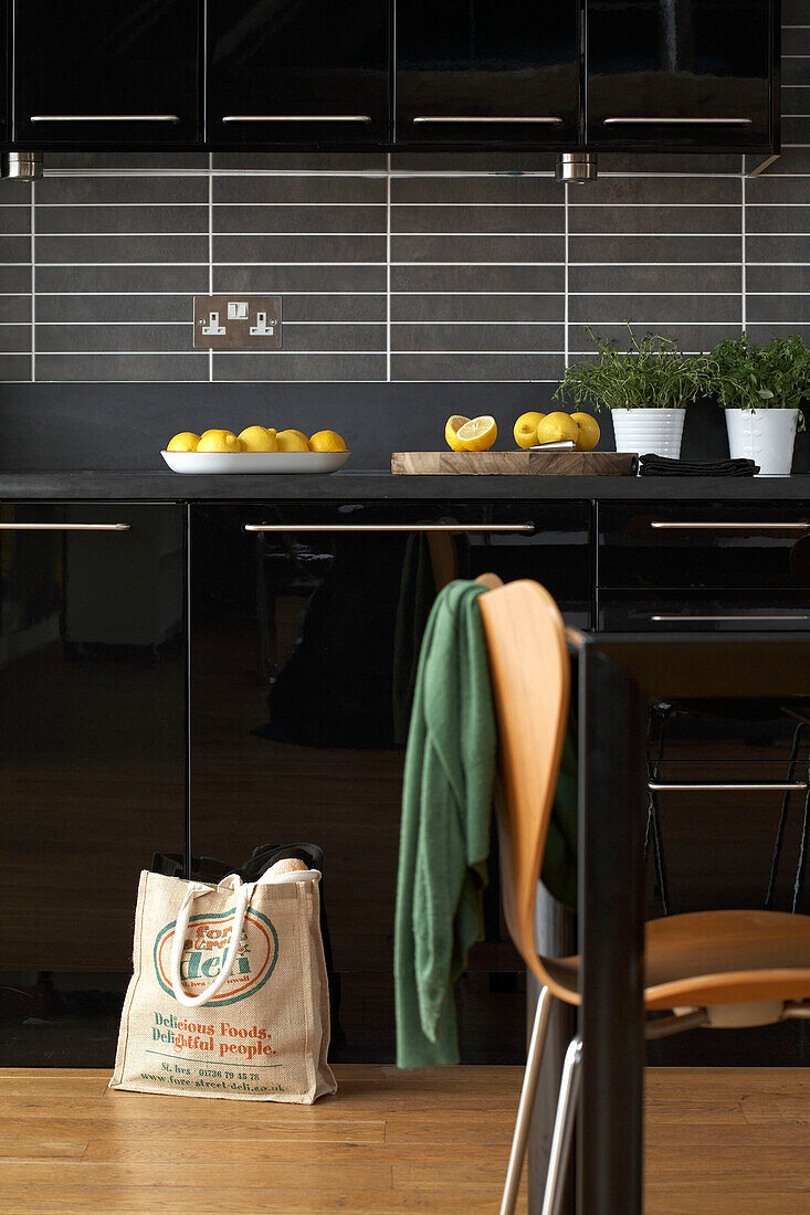 Cut lemons on work surface with grey splashback and black fitted units