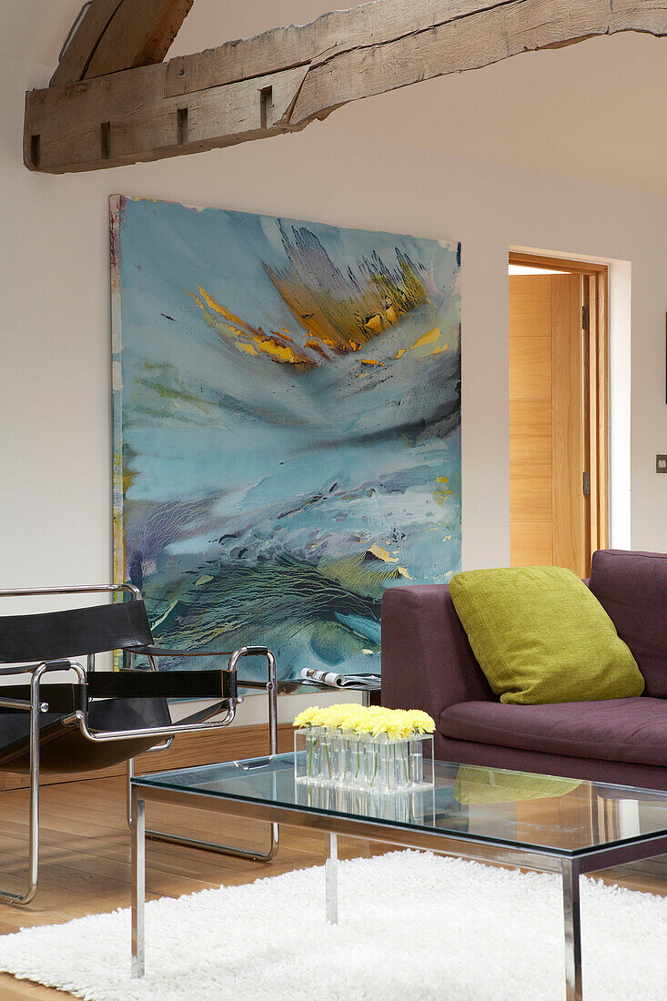 Oversized artwork in beamed living room with glass topped coffee table
