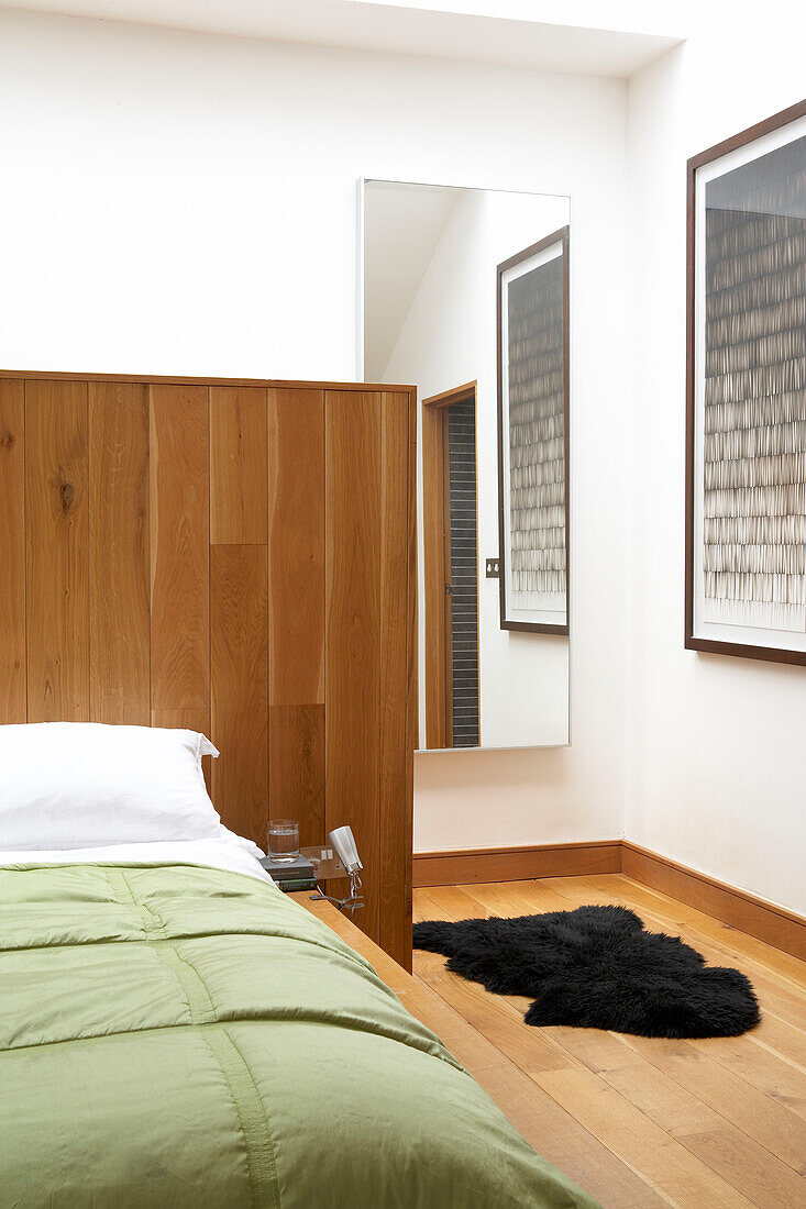 Schwarzer Schafsfellteppich auf dem Boden eines modernen Schlafzimmers mit Kopfteilwand