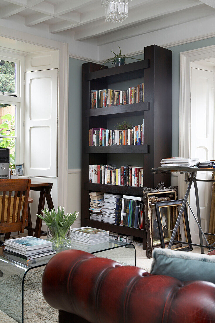 Bookshelf with picture frames between windows in living room of Bradbury home