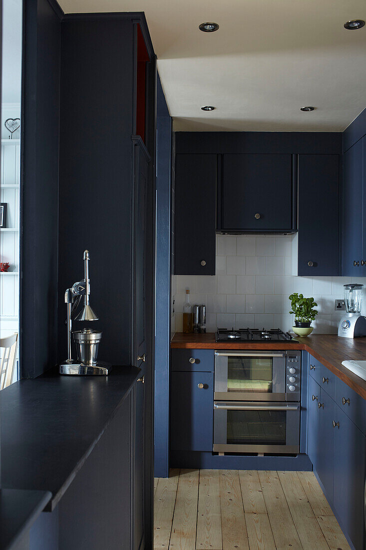Blue fitted galley kitchen in contemporary Bristol home, England, UK