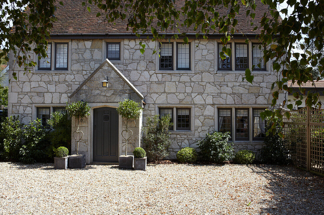 Steinfassade eines freistehenden Hauses mit Kiesauffahrt und Topfpflanzen in Brook, Isle of Wight, Vereinigtes Königreich