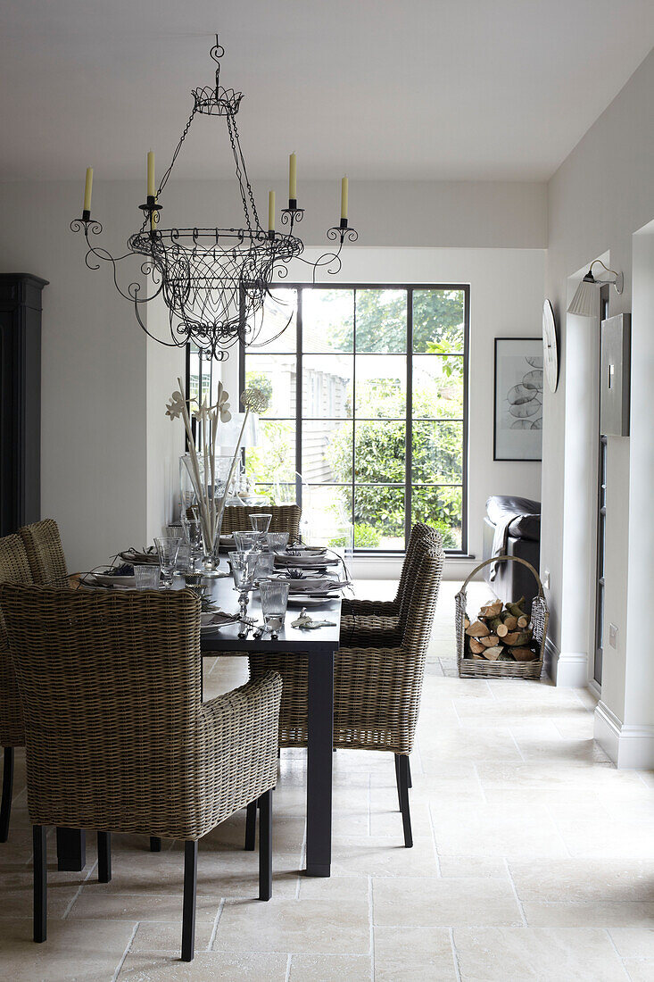 Dining table with wicker chairs and uncurtained picture window in Isle of Wight home, UK
