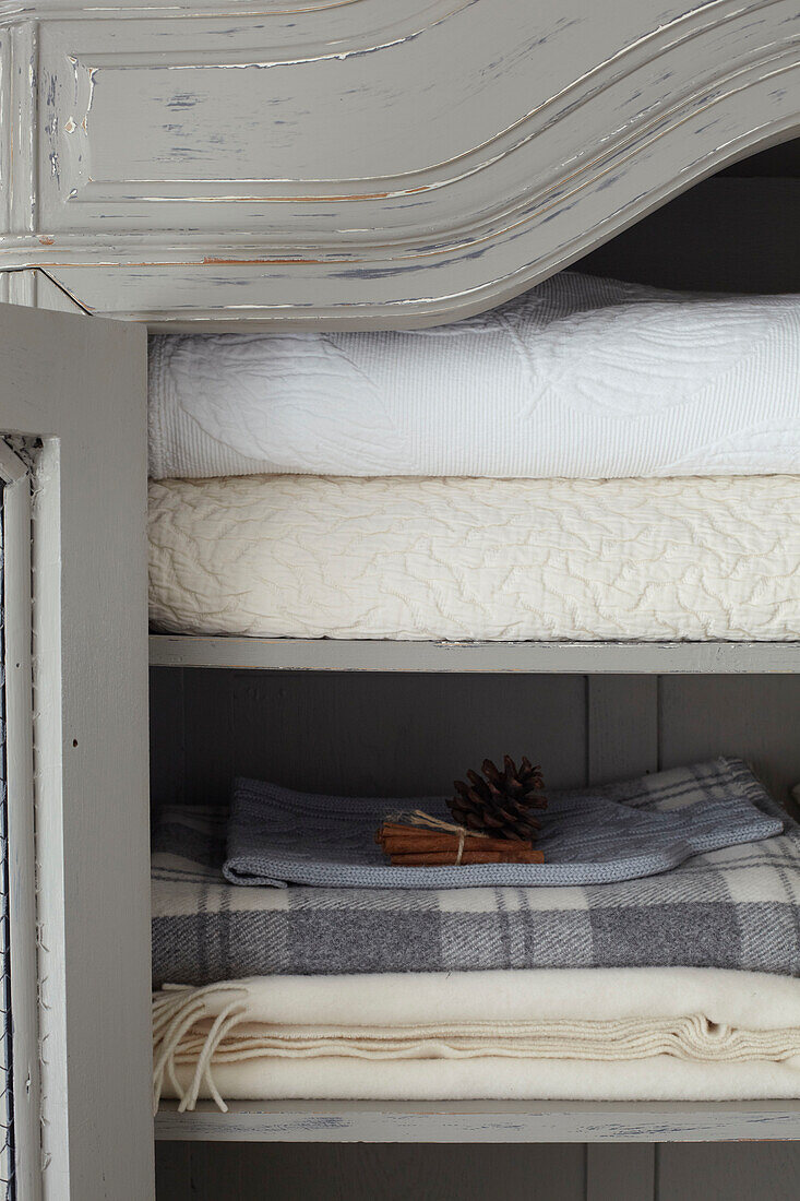 Mit Kiefernzapfen und Zimtstangen duftende gefaltete Decken und Bettbezüge in einem Haus auf der Isle of Wight, Vereinigtes Königreich