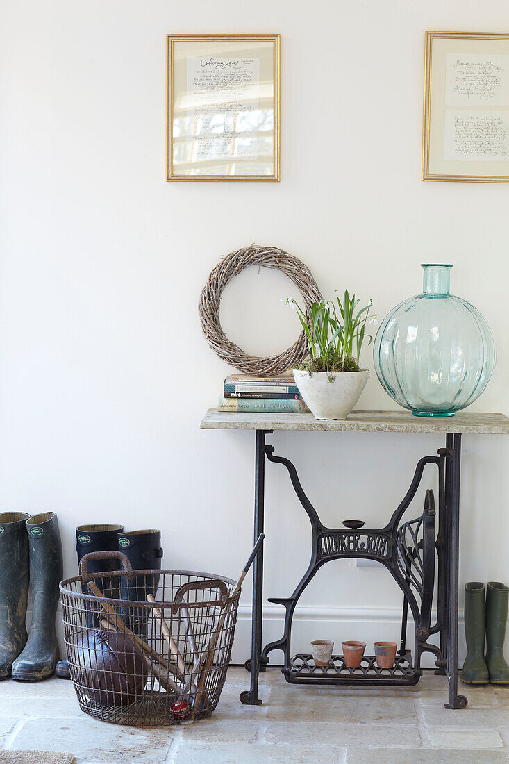 Wellington boots and metal basket with sewing machine table in Kent home, England, UK