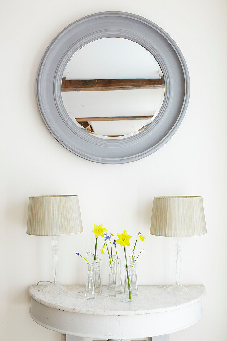 Narcissus on demi-lune with lamps and grey circular mirror, detail in Kent home, England, UK