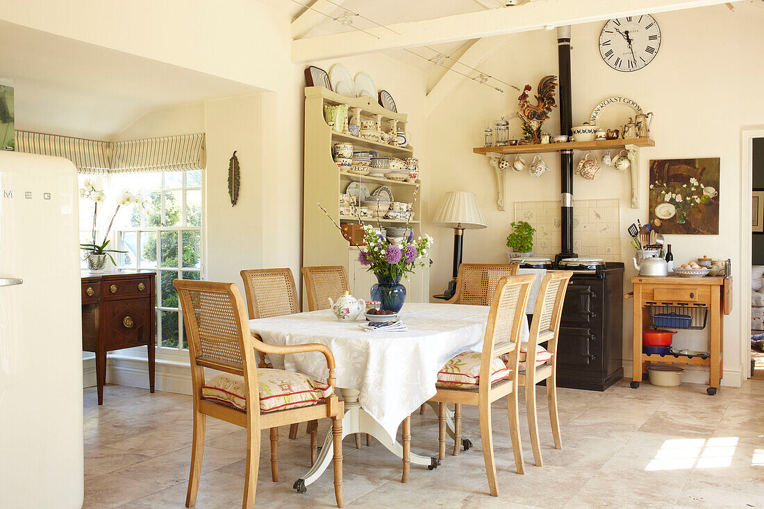 Wicker dining chairs at table in open plan Wiltshire country home, England, UK
