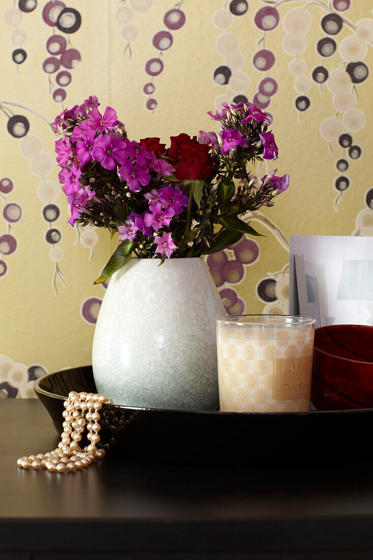 Schnittblumen und gemusterte Tapete in einem Londoner Schlafzimmer England UK
