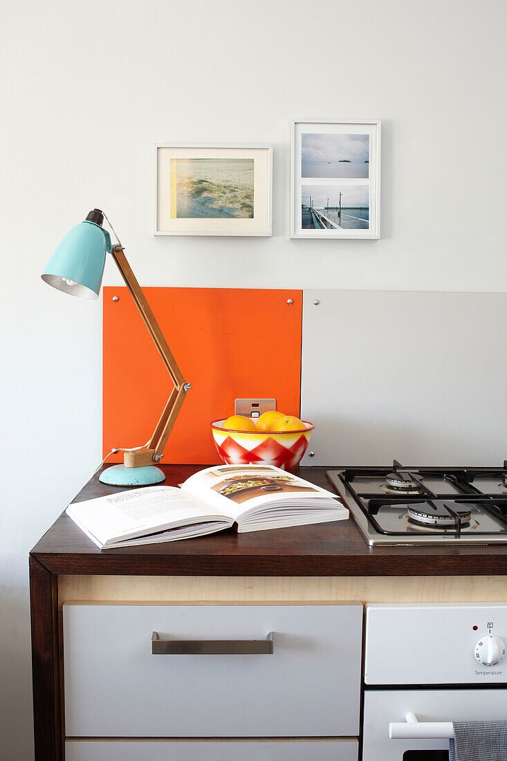 Schreibtischlampe auf Küchenarbeitsplatte mit offenem Rezeptbuch in einem Haus auf der Isle of Wight, UK