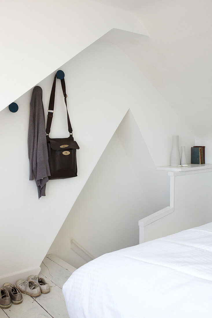 Bag and cardigan hang above footwear in bedroom of contemporary Weymouth beach house, Dorset, UK
