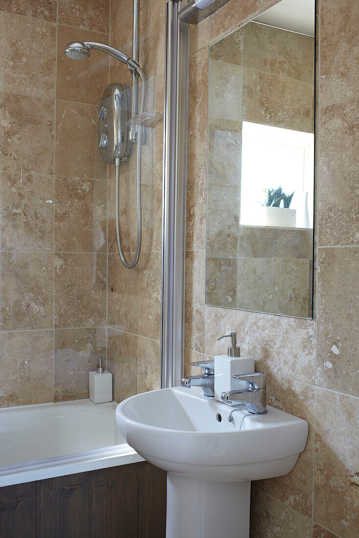 Rechteckiger Spiegel über dem Waschbecken in einem gefliesten Badezimmer mit Duschkabine in einem Haus in Weymouth, Dorset, UK