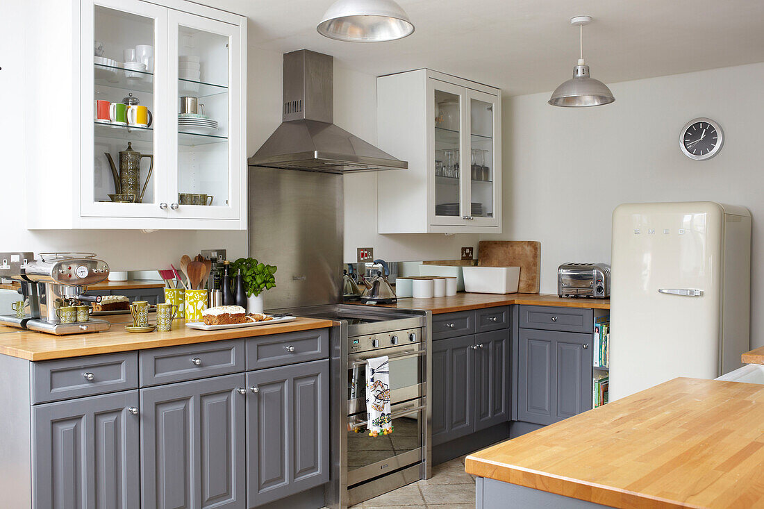 Grey fitted units with stainless steel extractor in Coombe cottage kitchen, UK