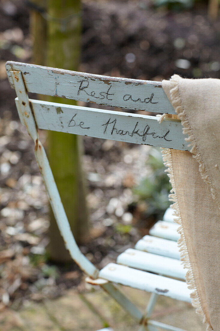 Klappstuhl mit Schriftzug 'Rest and be thankful' im Garten, St Lawrence, Isle of Wight, UK