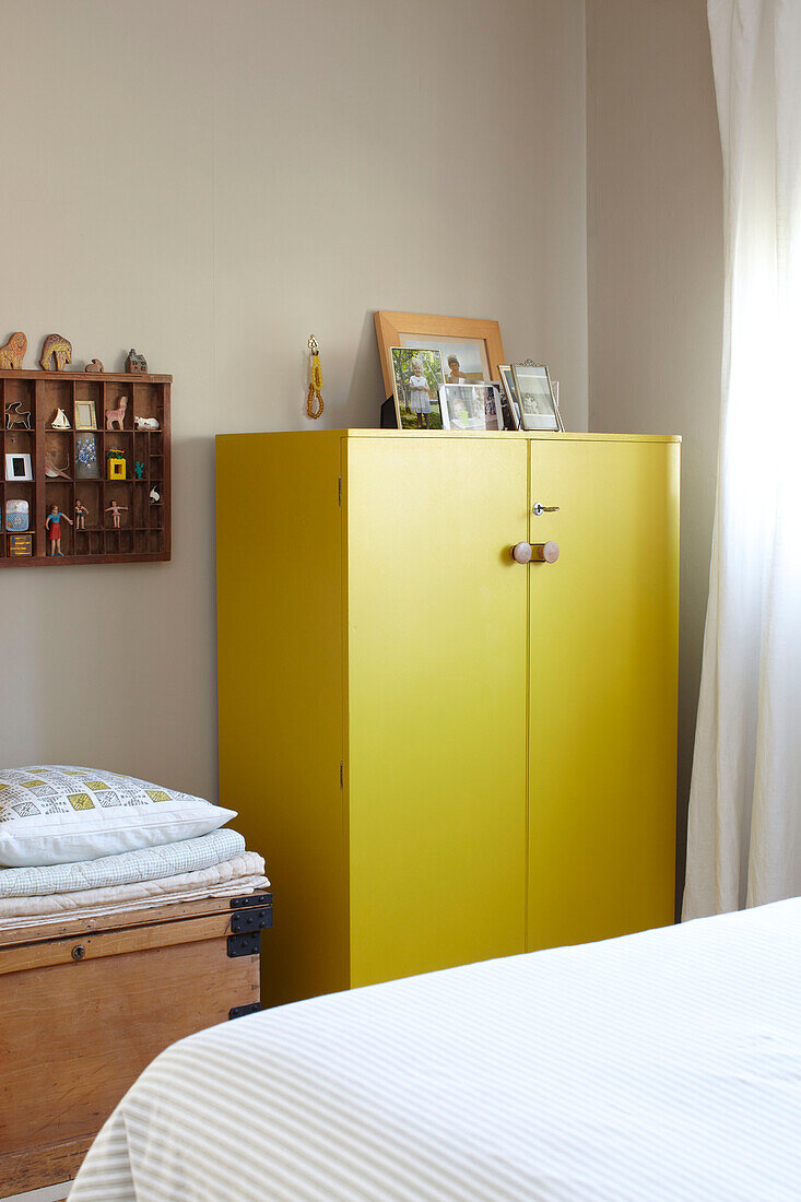 Familienfotos auf gelbem Schrank mit wandmontiertem Regal im Schlafzimmer in Ryde, Isle of Wight, UK