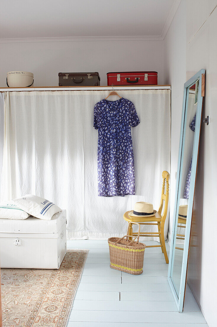 Vintage-Koffer über einem vorgehangenen Kleiderschrank mit blauem Kleid in einem Schlafzimmer in Ryde, Isle of Wight, UK