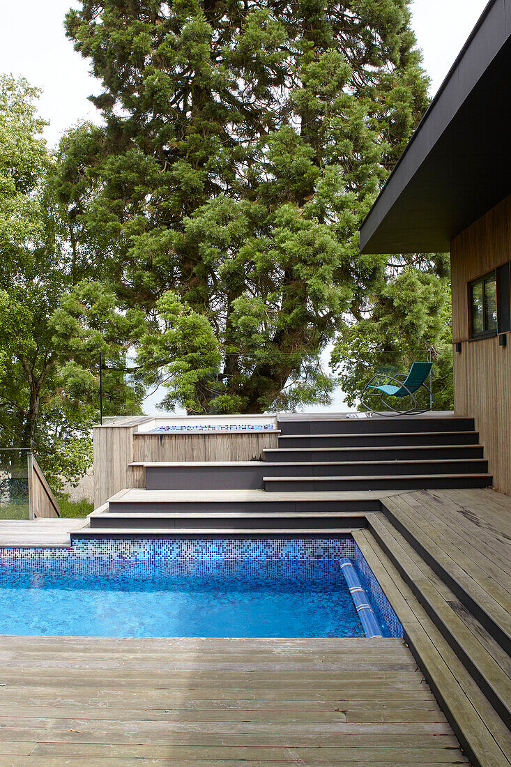 Holzterrassen und Bäume umgeben den luxuriösen Swimmingpool in einem Haus auf der Isle of Wight (UK)