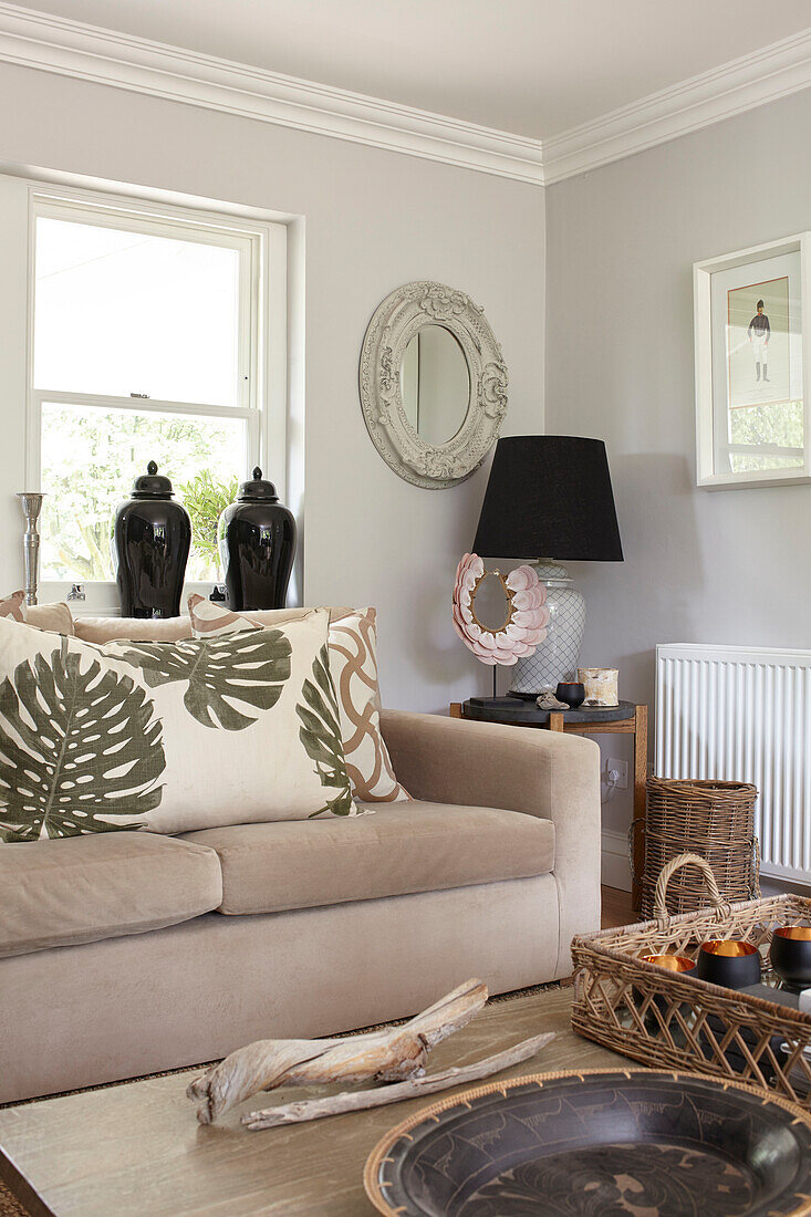 Kissen mit Palmenmuster auf dem Sofa mit schwarzer Lampe und Urnen Buckinghamshire UK