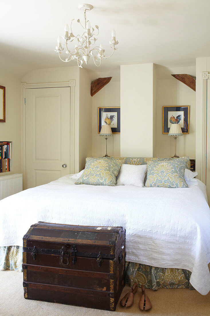 Double bed with travelling chest and artwork in Wiltshire country home, England, UK