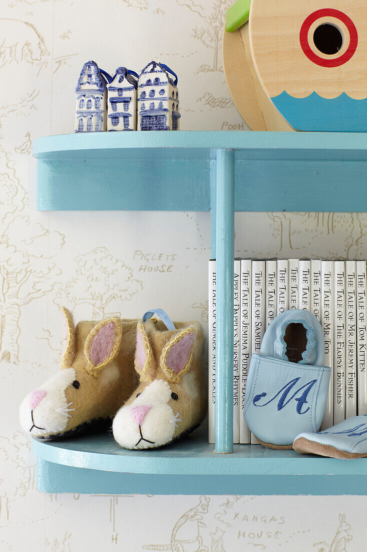 Kaninchenpantoffeln und Büchersammlung auf blau gestrichenen Regalen in einem Haus in Wiltshire, England, Vereinigtes Königreich