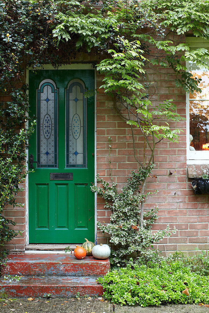 Gourds on front step with bright green front door, East Cowes home, Isle of Wight, UK