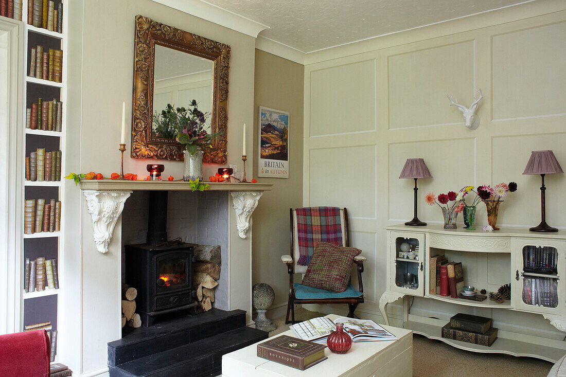 Carved mirror above fire with lit wood burner in East Cowes home, Isle of Wight, UK