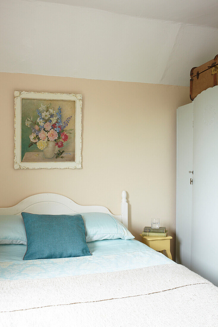 Türkisfarbenes Kissen auf einem Doppelbett unter einem Kunstwerk in einem Haus in East Cowes, Isle of Wight, UK