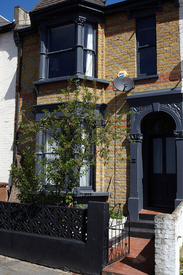 Brick exterior of London terraced house with black paintwork, England, UK