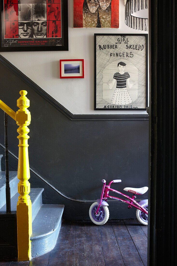Kinderfahrrad mit Vintage-Kunstwerken und gelbem Geländer in einem Londoner Haus, England, UK