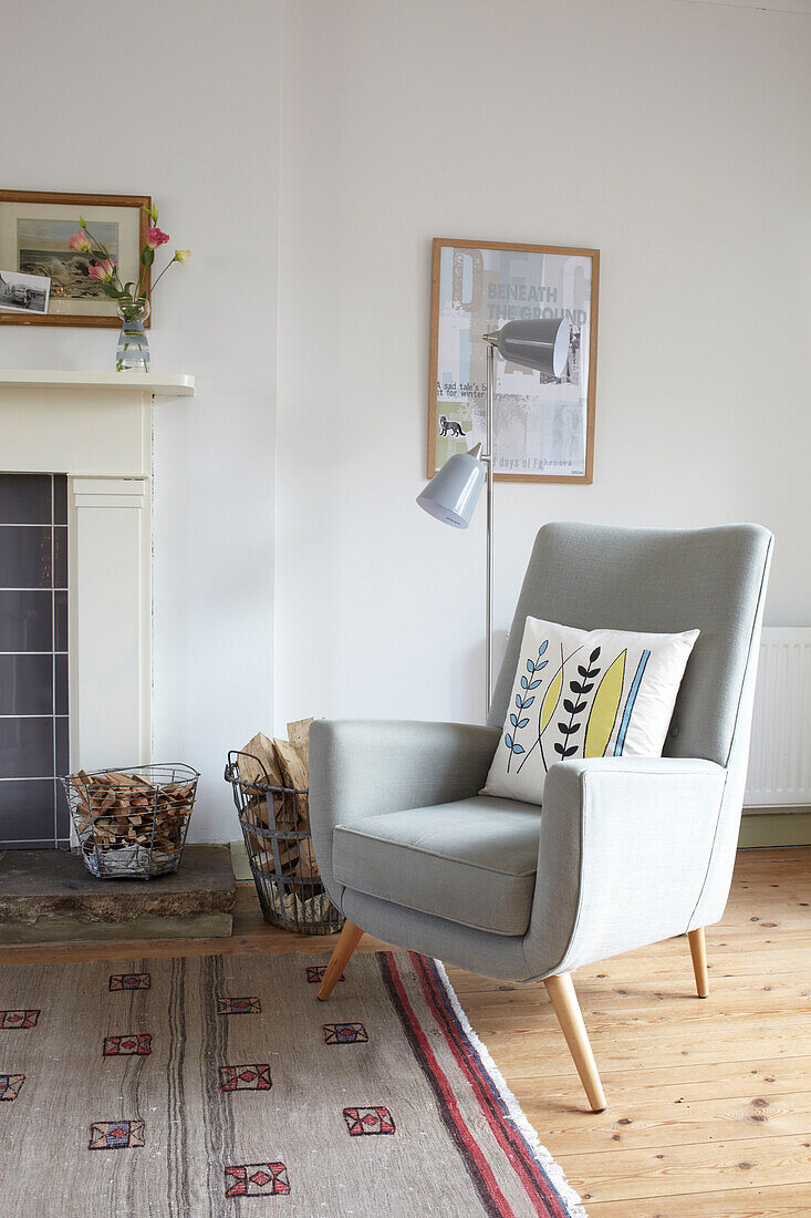 Light grey armchair with kindling at fireside in Ryde living room Isle of Wight, UK