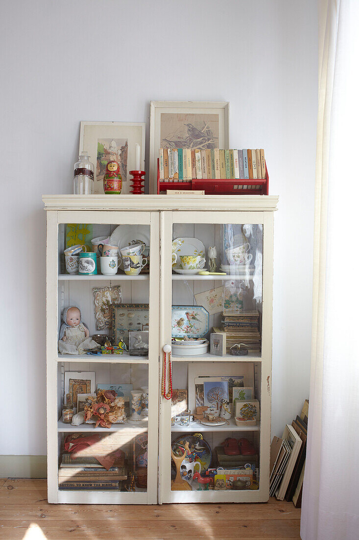 Glasvitrine mit Spielzeug und Büchern im Wohnzimmer in Ryde, Isle of Wight, Großbritannien