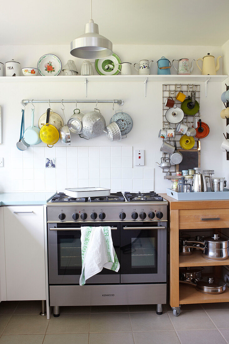 Colanders and jugs hang above range oven with baking tray on gas hob in Ryde kitchen Isle of Wight, UK