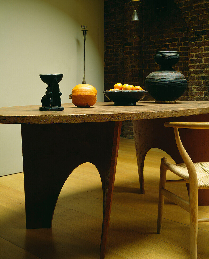 Esszimmer mit maßgeschneidertem ovalen Holztisch und afrikanischem Topf und Schale