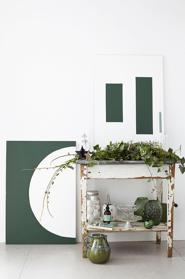 Mit Zink beschichteter Tisch mit grünen Glaswaren und geometrischem Kunstwerk