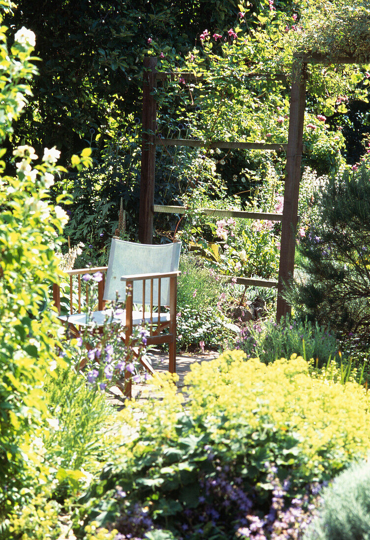 Gartenstuhl auf der Terrasse inmitten von Gartenlaub und Blumen