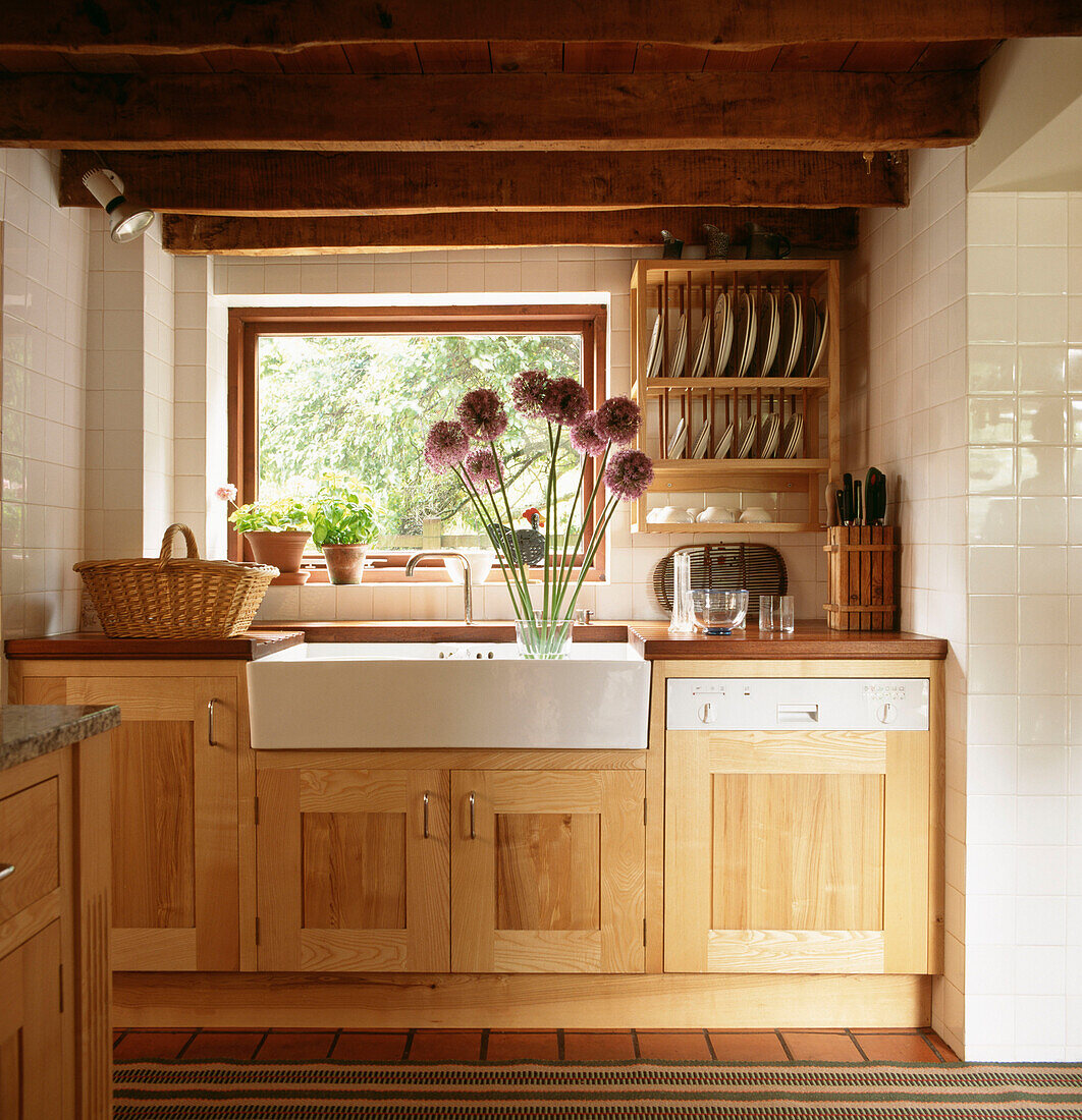 Modern country kitchen with wooden cupboards and butler sink with Alliums