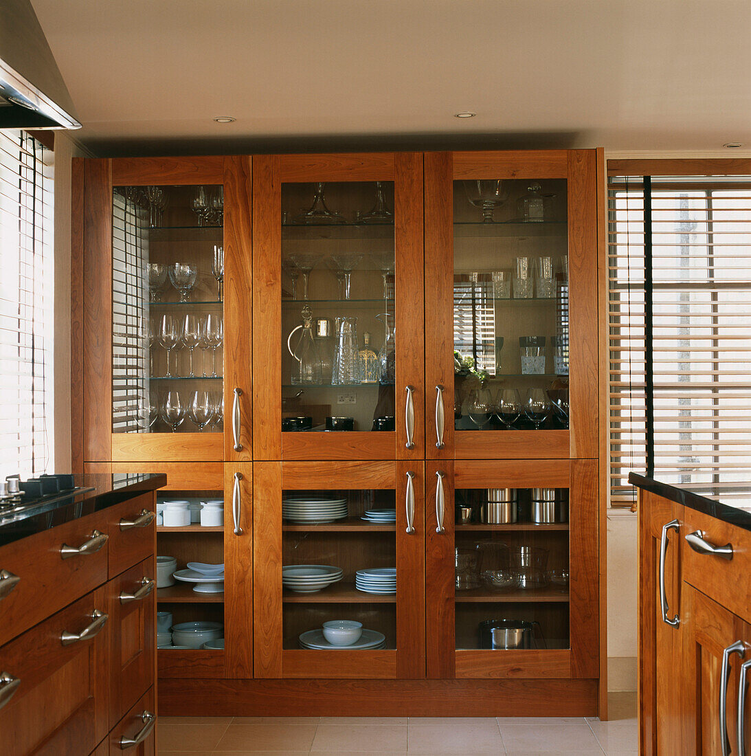 Küchenschränke aus Kirschholz und eine Kommode mit Glasfront, gefüllt mit Geschirr