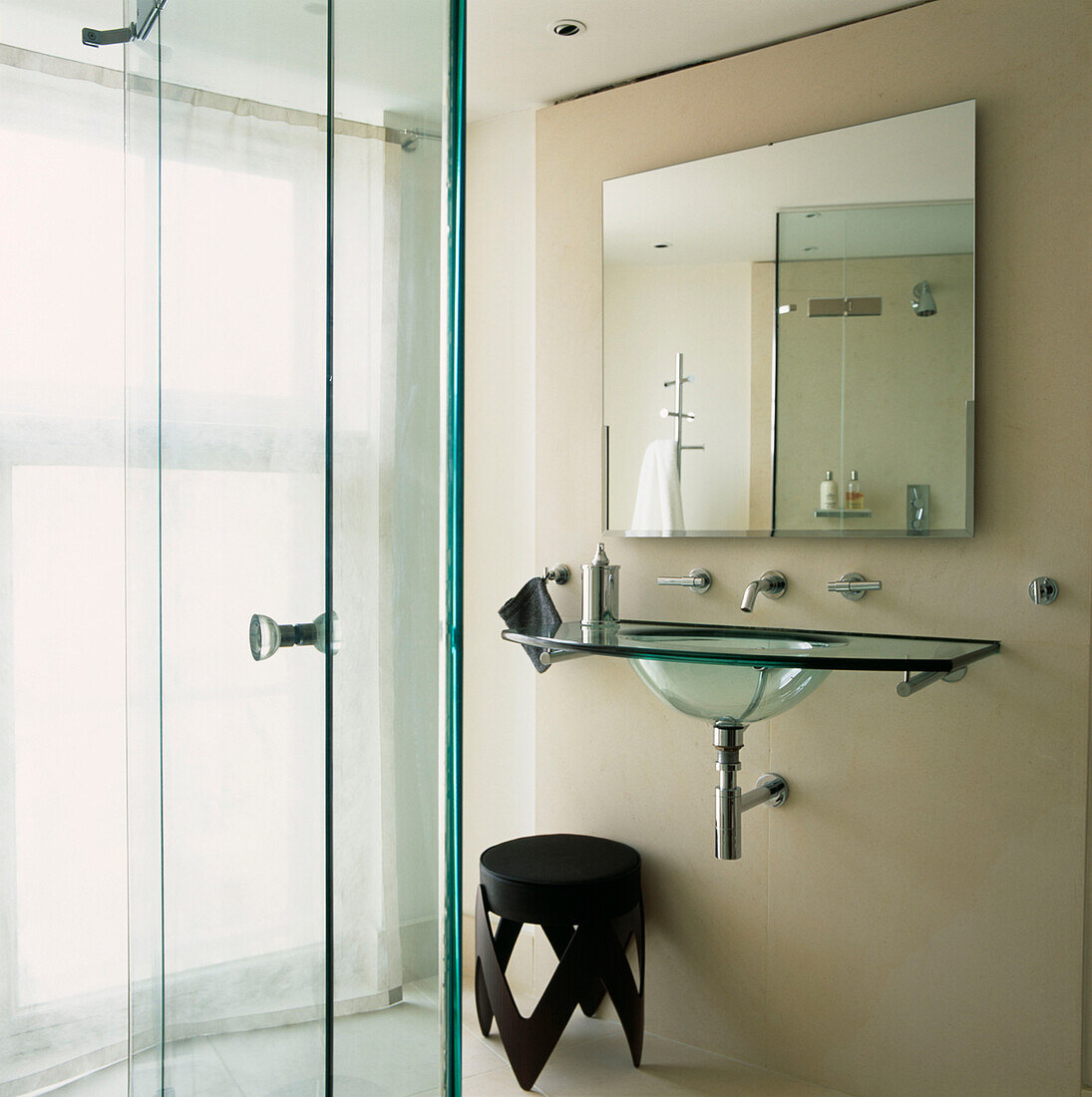 Badezimmer aus Kalkstein mit Glasduschtür und Glaswaschbecken