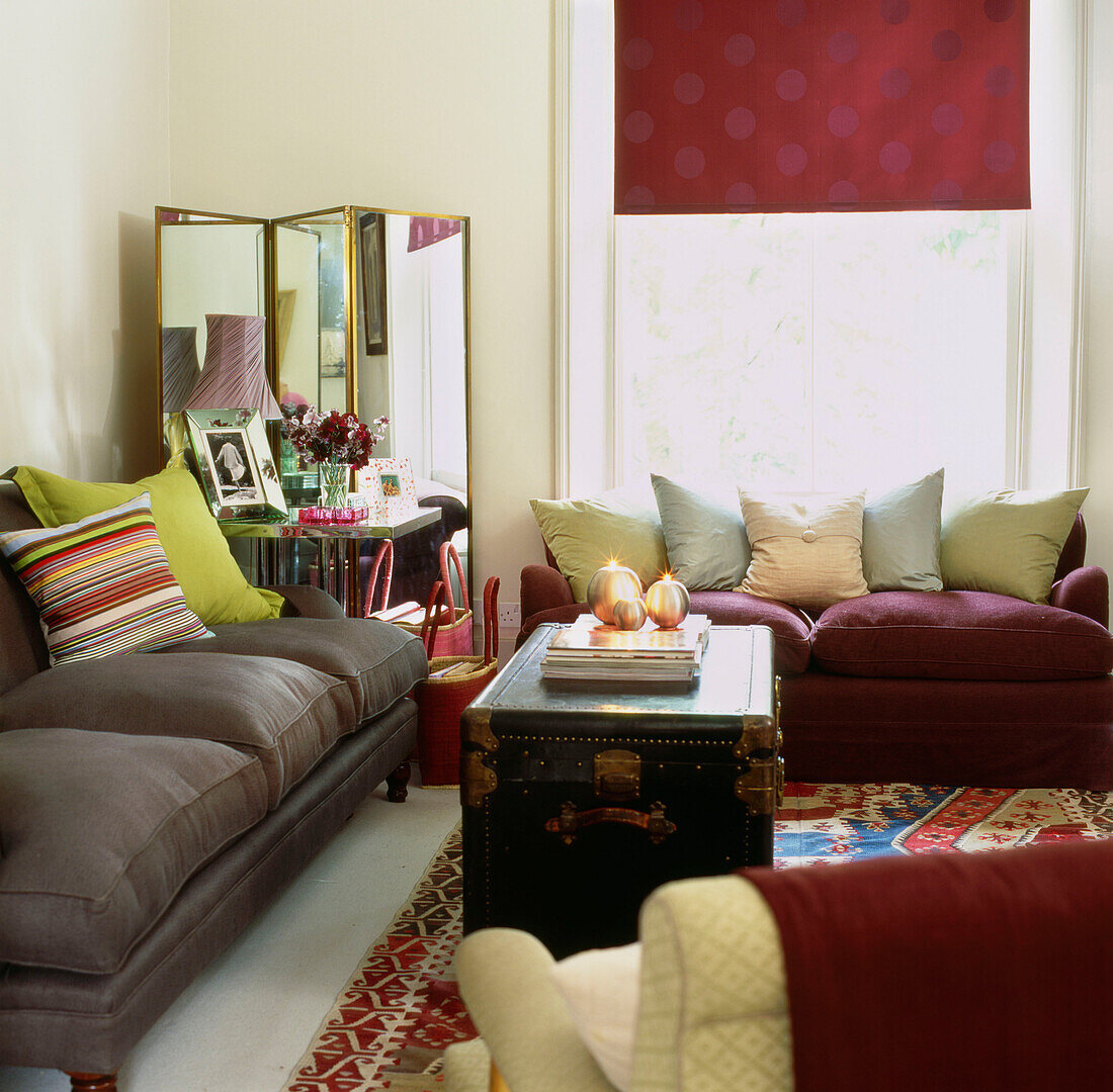 Colourful accessories in living room with two sofas and folding mirror