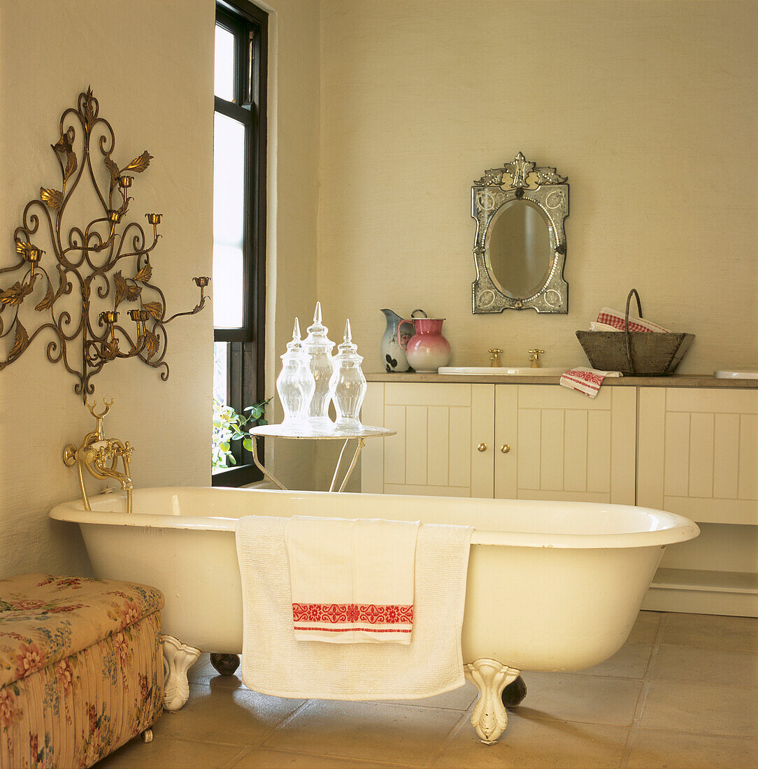 Rolltop-Badewanne in elegantem Badezimmer mit venezianischem Spiegel und dekorativer Wandverkleidung