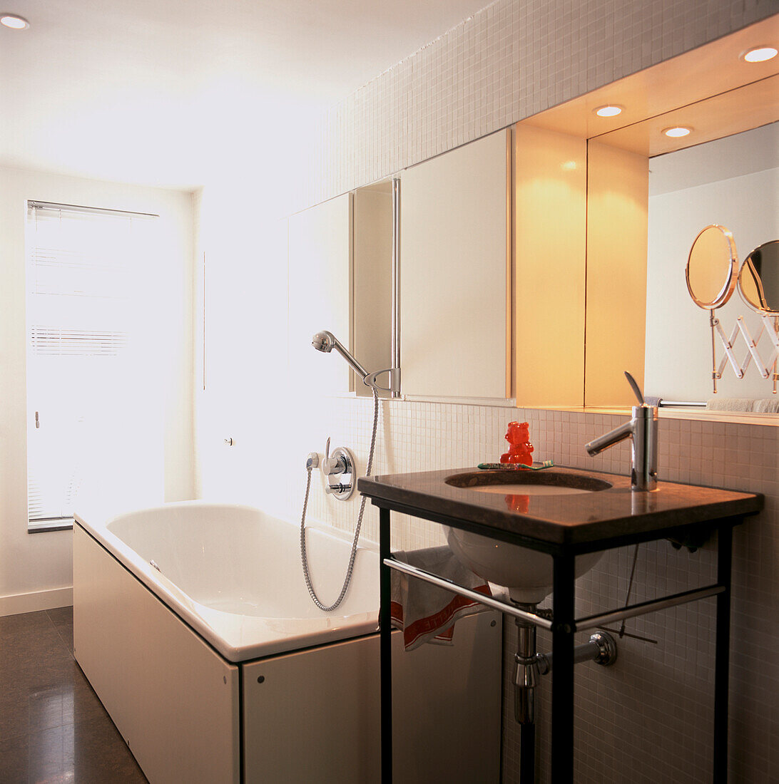 Weiße Wandmosaike in einem Badezimmer mit Badewanne, separatem Handwaschbecken und eingelassenem Spiegel
