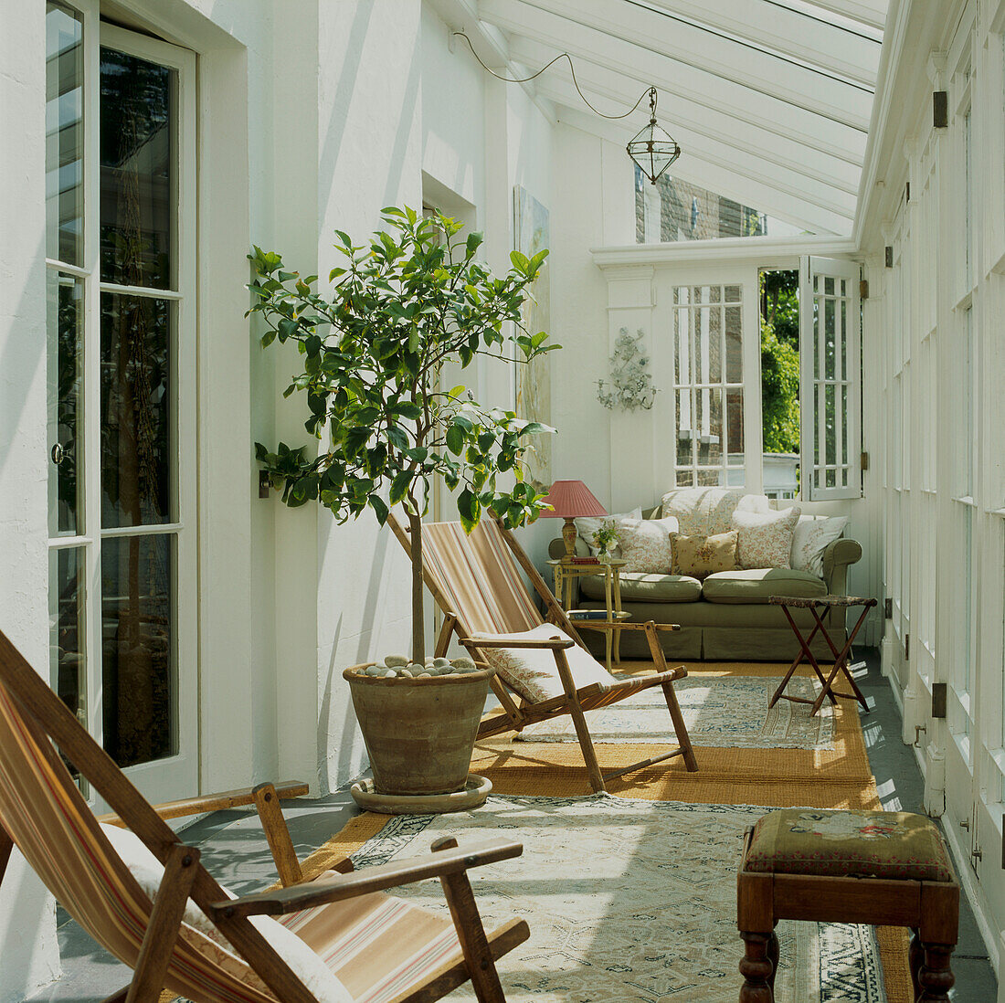 Deck chairs and orange trees in sunny white conservatory