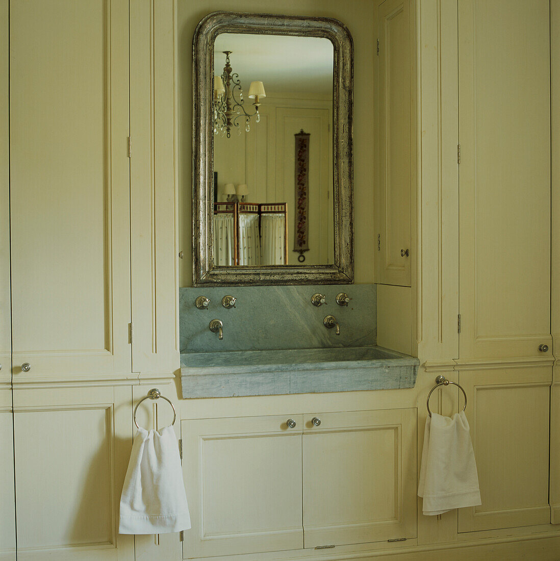 Antique marble basin set in bespoke cabinets with French mirror
