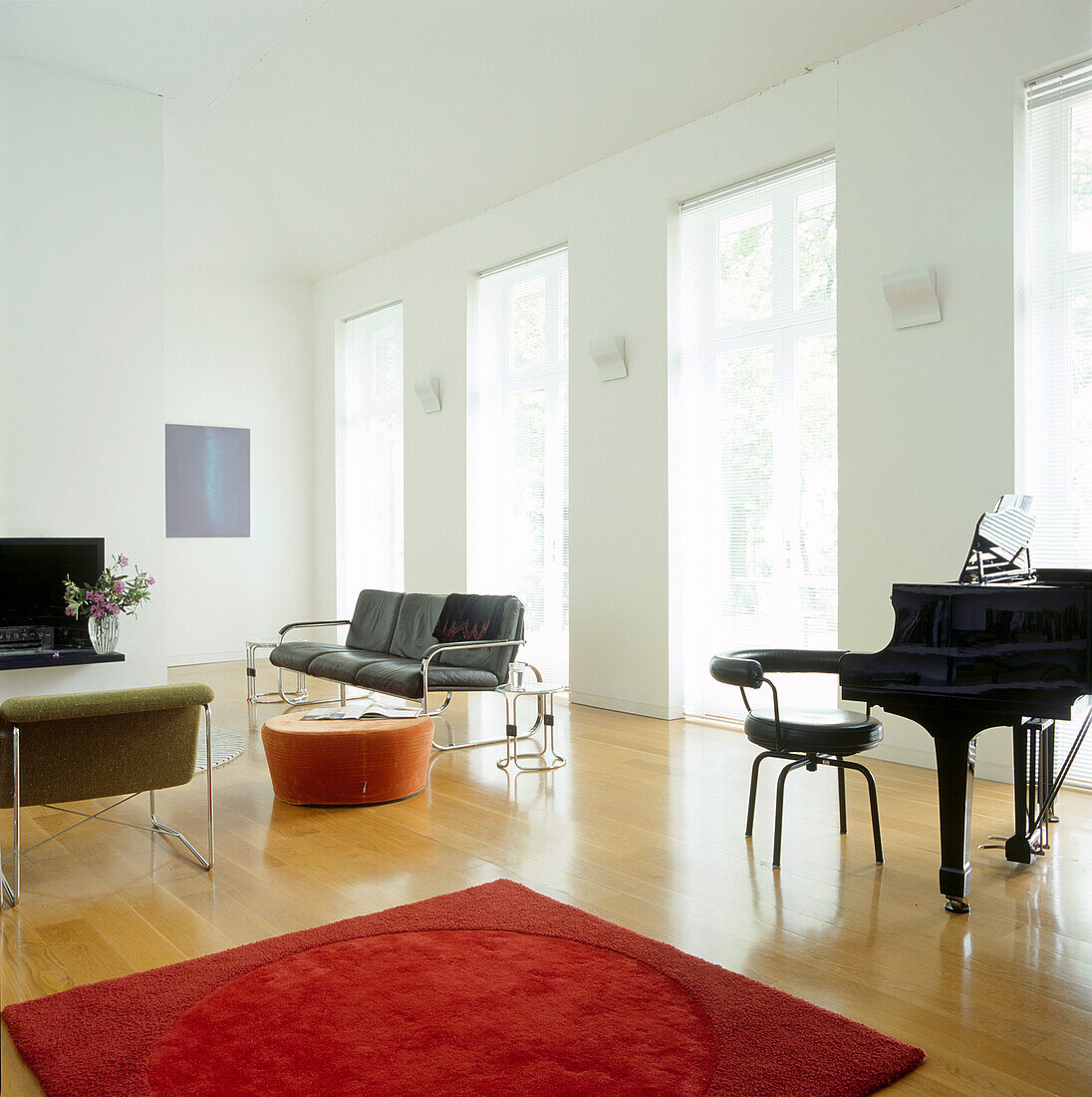 Bright and spacious living space with grand piano and modern black leather furniture