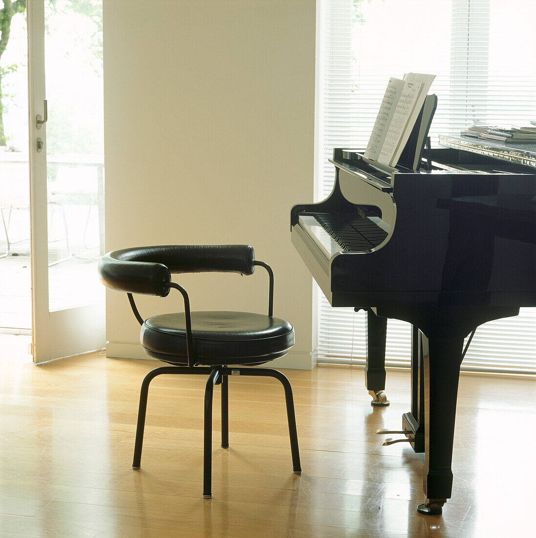 Close up of Le Corbusier stool in front of grand piano in bright living room