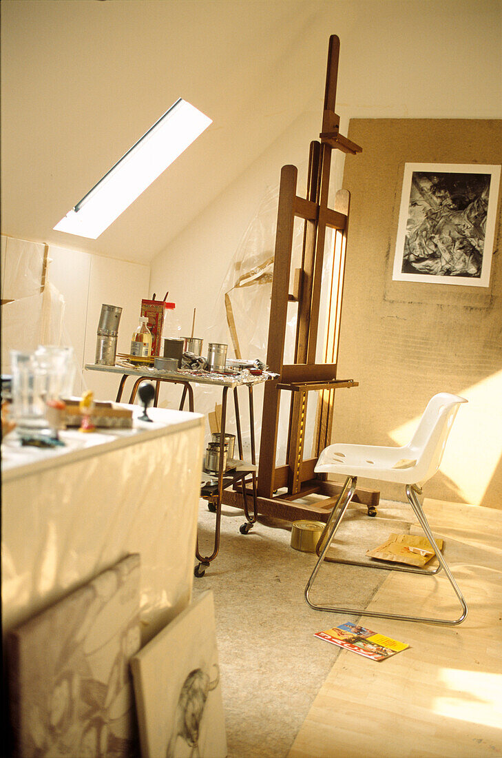 Working artist's attic studio with large easel and unfinished sketches 